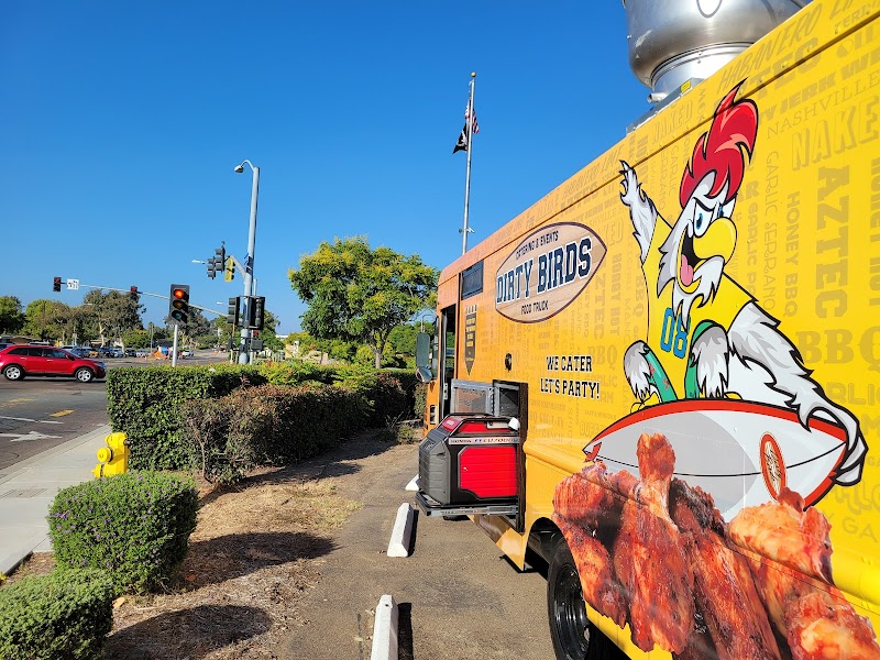 The orange Dirty Birds food truck parked beside a landscaped outdoor space